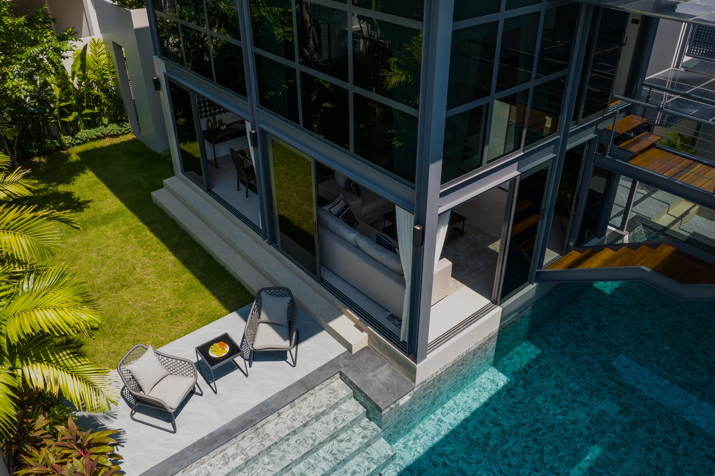 Вилла RIVERHOUSE Phuket с 3 спальнями тип A: панорамные окна на два этажа, бассейн в центре планировки, терраса с зоной отдыха и зеленый сад вокруг.